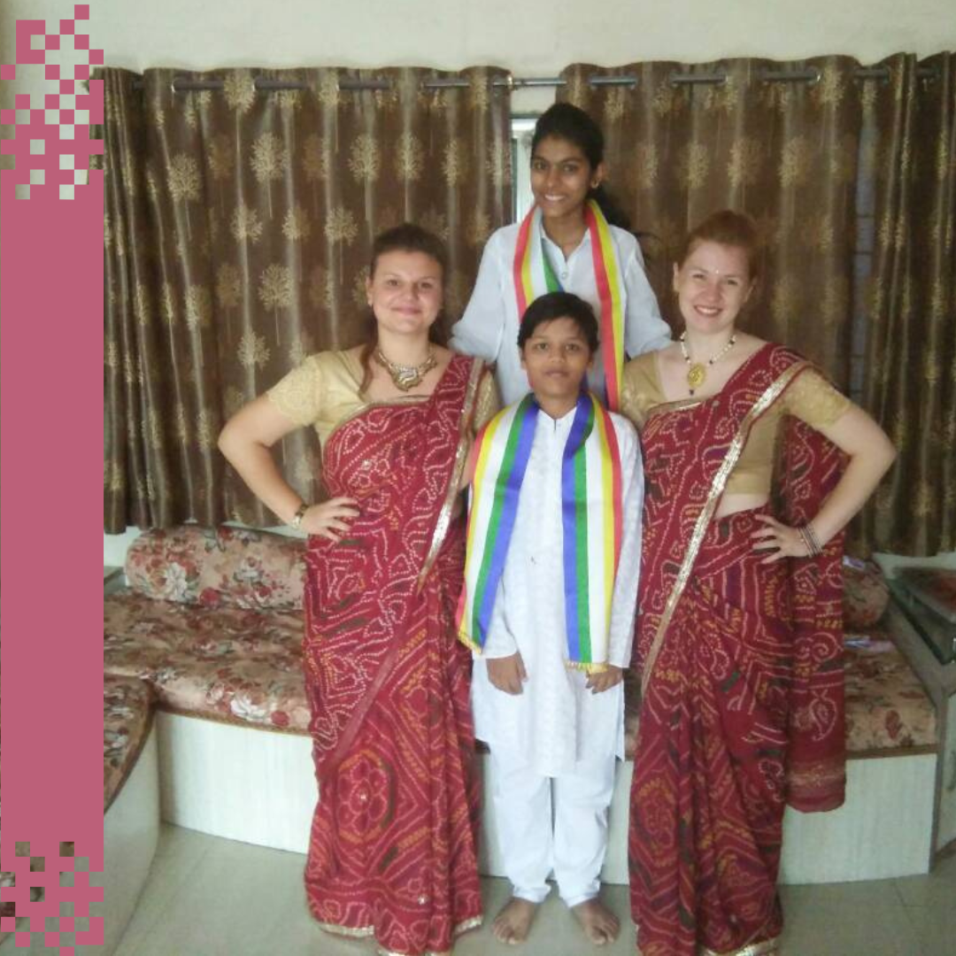 Mareike steht mit zwei kleinen Jungen und einer Mitfreiwilligen in traditionelle Gewänder gekleidet in der Mitte des Bildes.